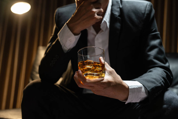 Επιχειρηματίας κάθεται κρατώντας ένα ποτήρι ουίσκι ποτό ουίσκι στην αίθουσα κάβα - Φωτογραφία, εικόνα