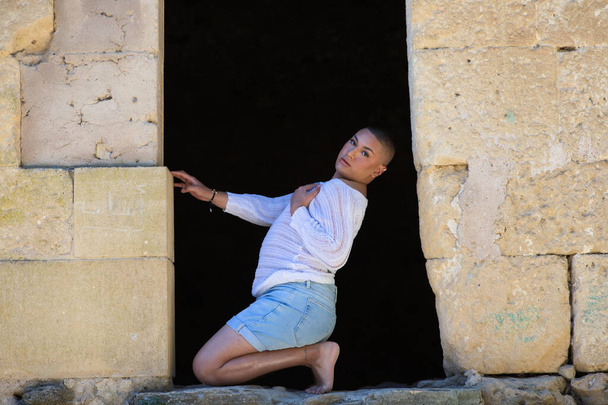 Non binary latin and young person, is in a castle making different body expressions in the hole of the door. Concept of diversity, homosexuality and gay pride - Photo, Image