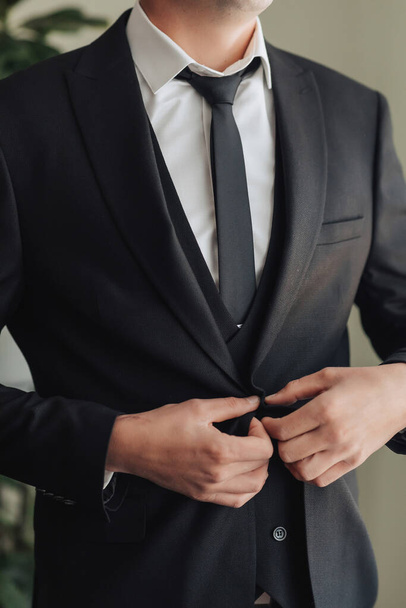cropped photo of a stylish man adjusting his jacket. Front view. A stylish watch. Men's style. Fashion. Business - Foto, afbeelding
