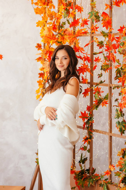 A young girl in autumn, in a white dress and jacket in autumn scenery with long loose hair curls. High quality photo - Foto, afbeelding