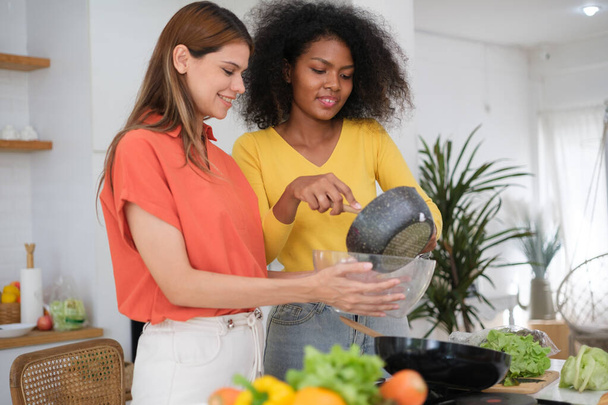 Multiracial Lesbian couple cooking salad in kitche - Foto, Bild