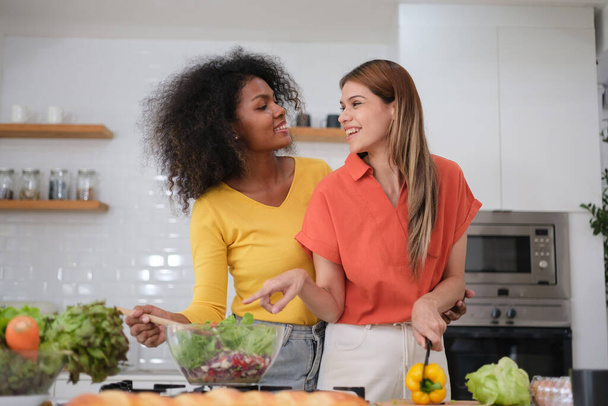 Multiracial Lesbian couple cooking salad in kitche - Фото, зображення