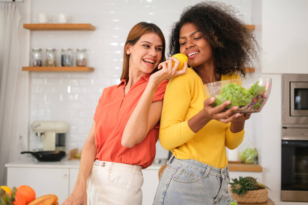 Multiracial Lesbian couple cooking salad in kitche - Zdjęcie, obraz