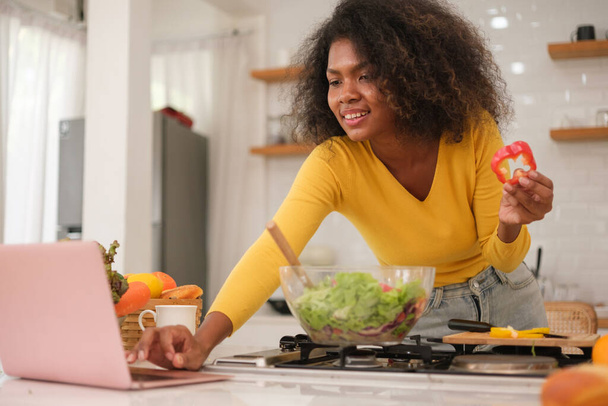 Multiracial jeune femme cuisine salade à la maison. - Photo, image