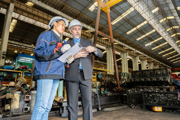 A business man inspects the work of an on-site worker at an old factory for rehearsing train engines.	 - Фото, зображення