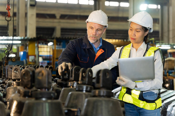 A business man inspects the work of an on-site worker at an old factory for rehearsing train engines. - Foto, Bild