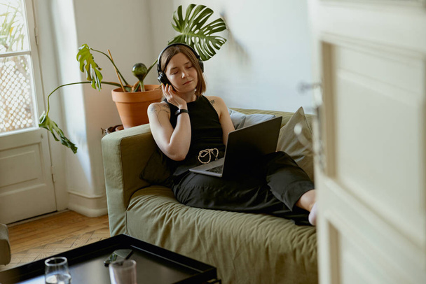 Een vrouw in een koptelefoon houdt van e-learning van vreemde talen. Zelfstudie draadloos technologisch gebruiksconcept - Foto, afbeelding