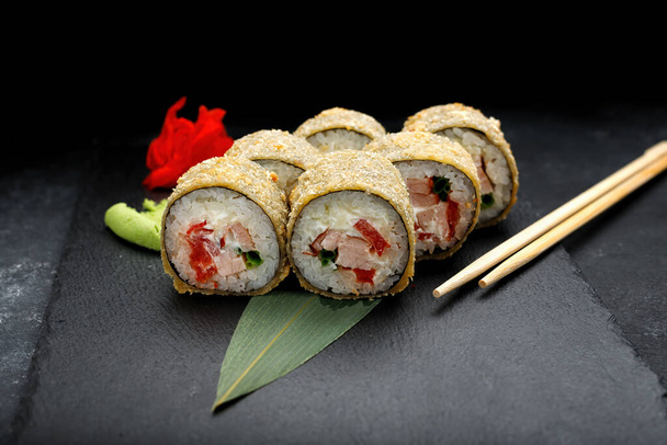 Rotolo di sushi caldo con tonno su una pietra nera con zenzero e wasabi - Foto, immagini