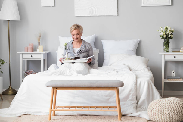 Mature woman having breakfast in bed - Photo, Image