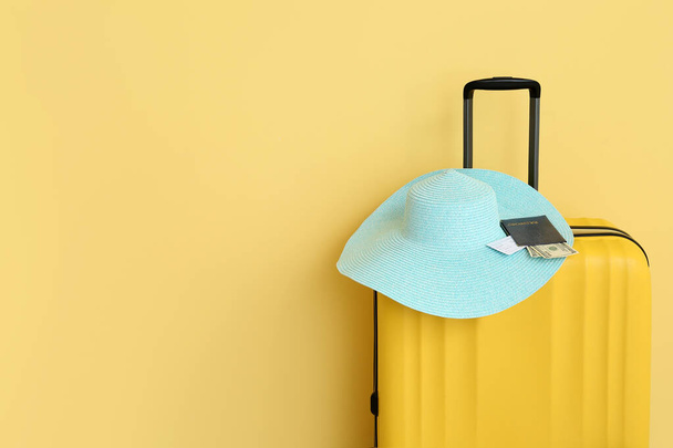 Валіза з плетеним капелюхом, паспортом, квитком і грошима на жовтому тлі. Концепція подорожей - Фото, зображення