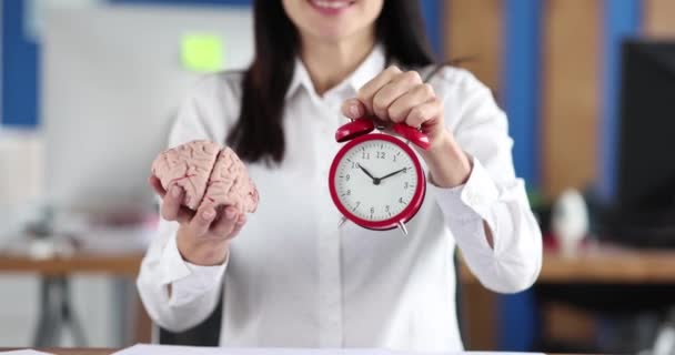 Woman holding artificial human brain and alarm clock near documents with graphs 4k movie slow motion. How to optimize paperwork concept - Video
