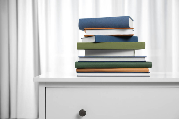 Hardcover books on white chest of drawers indoors - Fotoğraf, Görsel