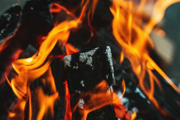 A bright flame of fire over a campfire. Wooden wood stacked in a pyramid is burning. The flame of fire close-up. White smoke rises over the fire. Barbecue bonfire. Tourist concept - Photo, image