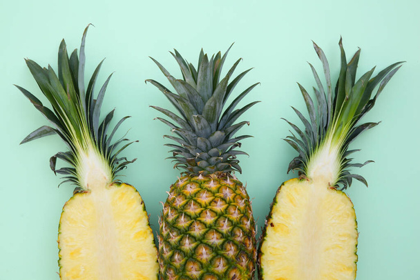 Whole and cut ripe pineapples on light green background, flat lay - Fotoğraf, Görsel