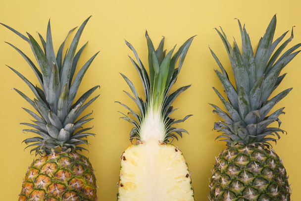 Whole and cut ripe pineapples on yellow background, flat lay - Foto, Bild
