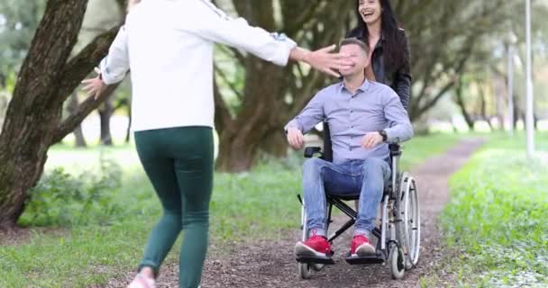Jeune femme étreint homme heureux dans un fauteuil roulant sur la promenade dans le parc 4k film. Amis soutien psychologique pour les personnes handicapées concept - Séquence, vidéo