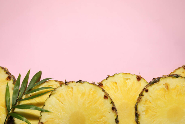 Slices of tasty ripe pineapple and green leaves on pink background, flat lay. Space for text - Valokuva, kuva