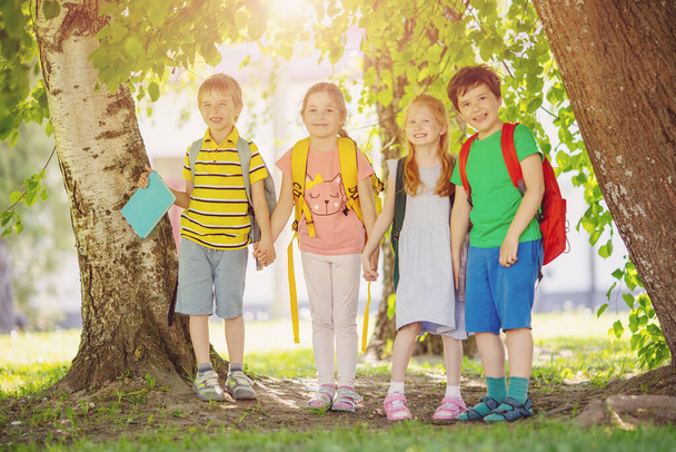 Group of children standing with backpacks near the school. Concept of the back to school and friendship. - Fotografie, Obrázek