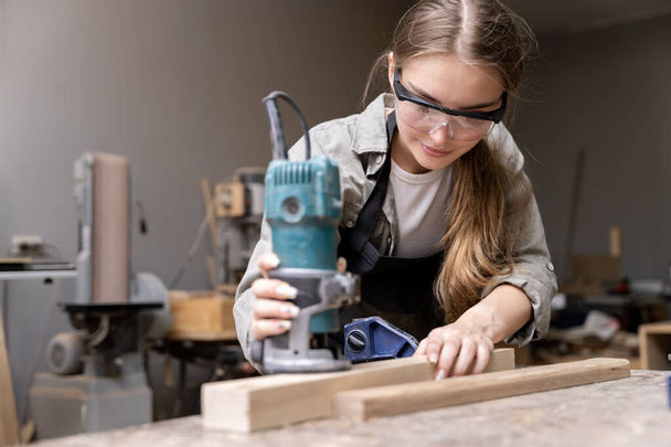 Portrait d'une menuisière utilisant des outils pour fabriquer des meubles dans une usine de meubles. avec des outils modernes - Photo, image