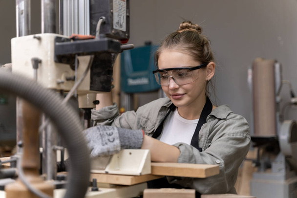 Portrait of a female carpenter using tools or machines for cutting, not drilling, wood to make furniture in a furniture factory. with modern tools - Фото, зображення
