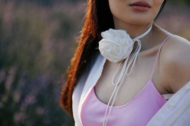 Closeup view to young woman with floral decor in form of white rose on her neck. - Valokuva, kuva