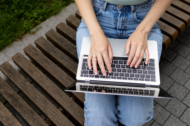 Una chica joven escribe en el teclado de un ordenador portátil, ordenador, vista lateral, vista superior - Foto, imagen