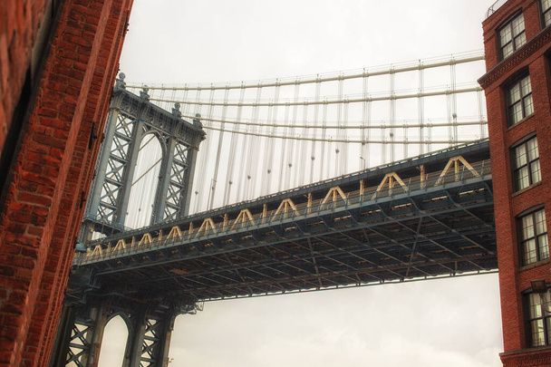 Ammirate l'accattivante vista del Manhattan Bridge perfettamente incastonato tra gli affascinanti edifici di Dumbo un perfetto mix di architettura urbana e bellezza naturale - Foto, immagini