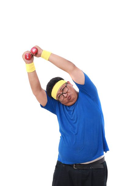 Asian overweight man in sportswear standing while holding dumbbell. Isolated on white background - Fotó, kép