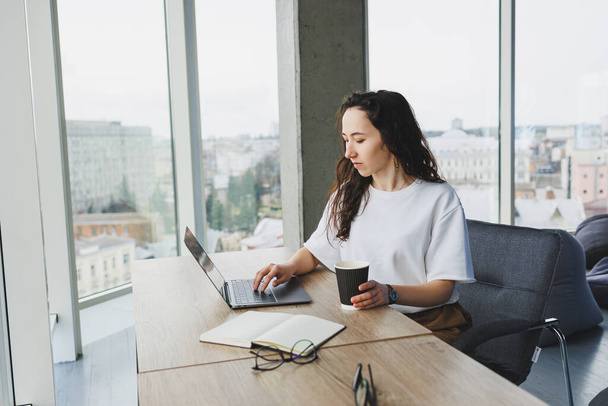 Modern irodai nő alkalmi ruhában dolgozik egy laptopon. Női menedzser a munkahelyen dolgozik az új projekten laptoppal. modern munkaterület - Fotó, kép