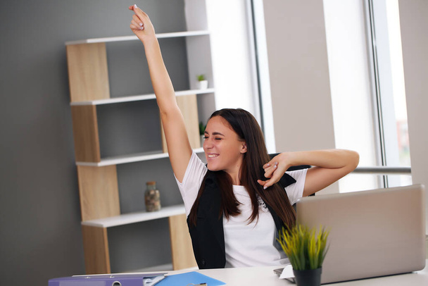 Happy businesswoman with raised so hand gesture reading letter on desk in front of laptop. The businessman is satisfied with the good news from the correspondence - Zdjęcie, obraz