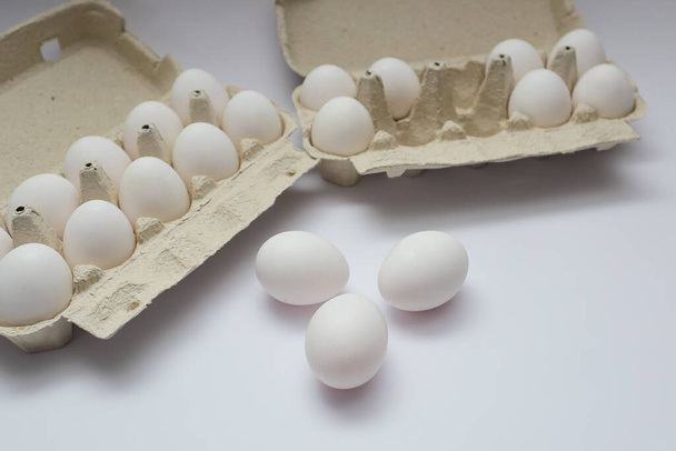Granja huevo fresco crudo en paquete en la mesa blanca. Cajas de huevos abiertas con pocos huevos blancos aislados sobre fondo blanco con ruta de recorte. - Foto, imagen