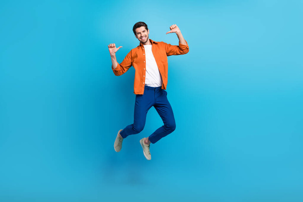 Full length portrait of crazy carefree active man jumping point fingers self himself isolated on blue color background. - Фото, зображення