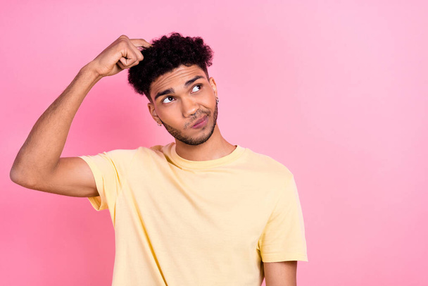 Photo of ponder pensive guy with earrings dressed stylish yellow t-shirt look empty space finger on head isolated on pink color background. - 写真・画像