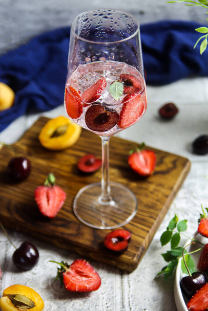 Sparlking wine with berries. Refreshing cooling sparkling summer drink with fresh strawberry, cherry and ice cubes. Prosecco champagne with ice cubes and berries - Foto, Imagen