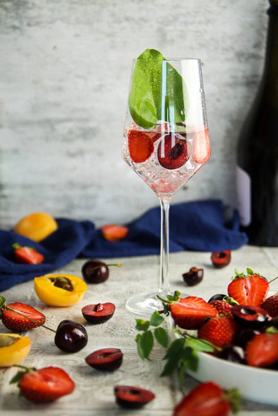 Sparlking wine with berries. Refreshing cooling sparkling summer drink with fresh strawberry, cherry and ice cubes. Prosecco champagne with ice cubes and berries - Foto, Imagen