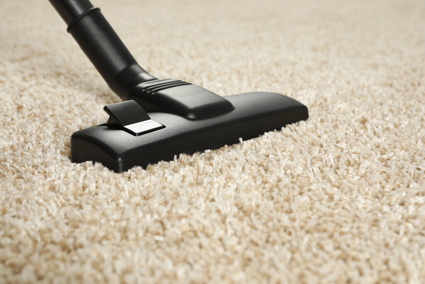 Hoovering beige carpet with modern vacuum cleaner, closeup. Space for text - Fotó, kép