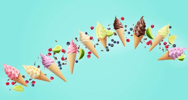 Delicious different ice cream, raspberries, blueberries, pieces of lime and chocolate falling on light blue background - Fotografie, Obrázek