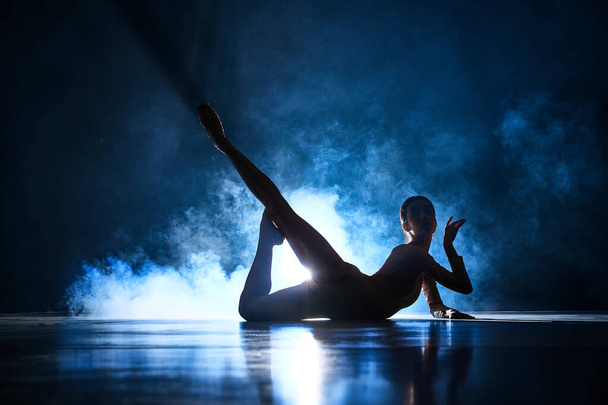 Ніжність і чуттєвість. Витончена, красива, елегантна жінка, балерина робить виступ на темно-синьому фоні з прожектором. Концепція мистецтва, класичний балет, хореографія, краса, реклама - Фото, зображення
