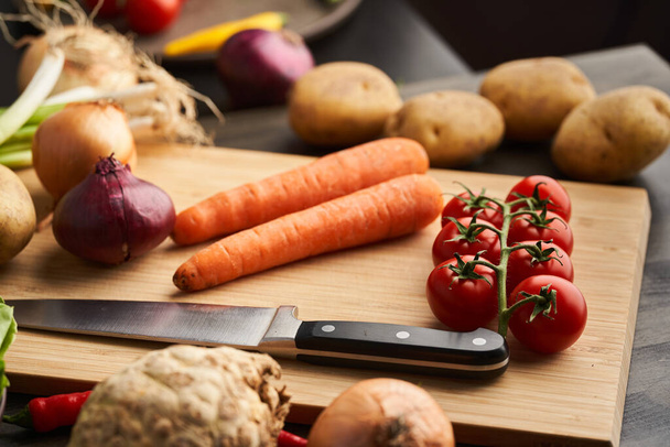 Closeup of a collection of various vegetables on the chopping board with a knife - Photo, image