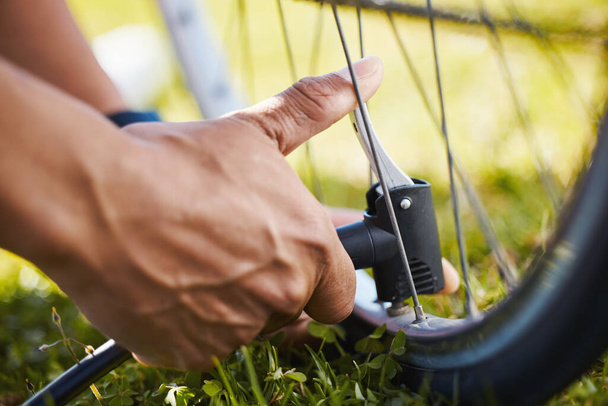 Fixing, bicycle and a man with air in wheel for maintenance, safety or repair while cycling. Bike, hands and a sports person or athlete with a pump or tools for flat tire or broken transportation. - Photo, Image