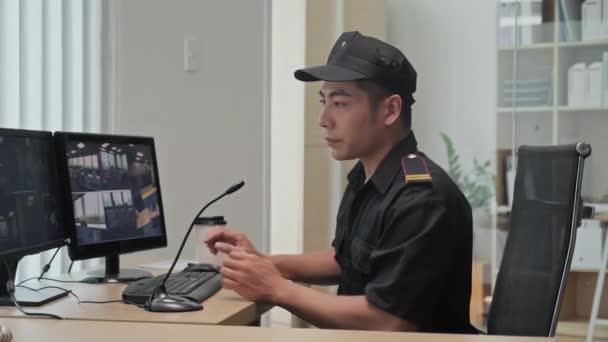 Portret strażnika w mundurze ochronnym patrzącego na kamerę siedzącą w miejscu pracy - Materiał filmowy, wideo