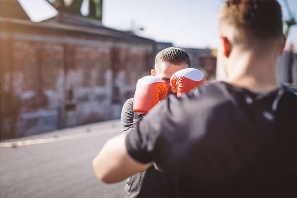 Dos hombres hacen entrenamiento de boxeo en el techo del edificio en la zona industrial de la ciudad, boxeando y luchando - Foto, imagen