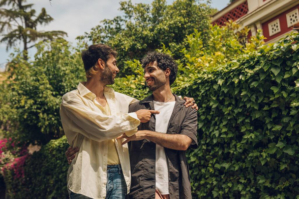 Zwei junge Männer unterhalten sich und lachen im Garten. Männer, die gemeinsam Spaß haben. - Foto, Bild