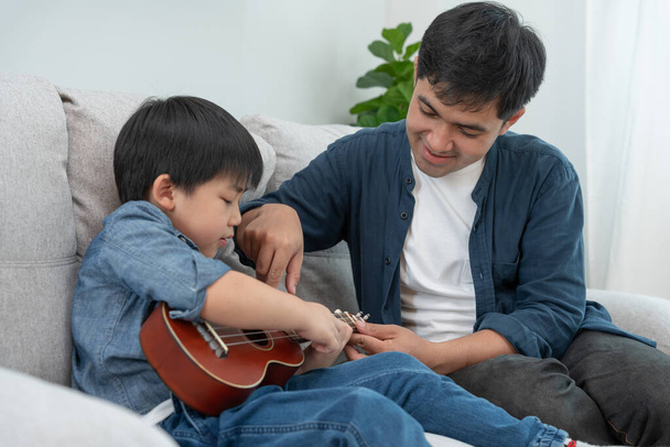Szczęśliwy samotny ojciec grający muzykę z małym chłopcem. Zabawna rodzina jest szczęśliwa i podekscytowana w domu. Ojciec i syn dobrze się bawią spędzając razem czas. Czas wolny, wakacje - Zdjęcie, obraz