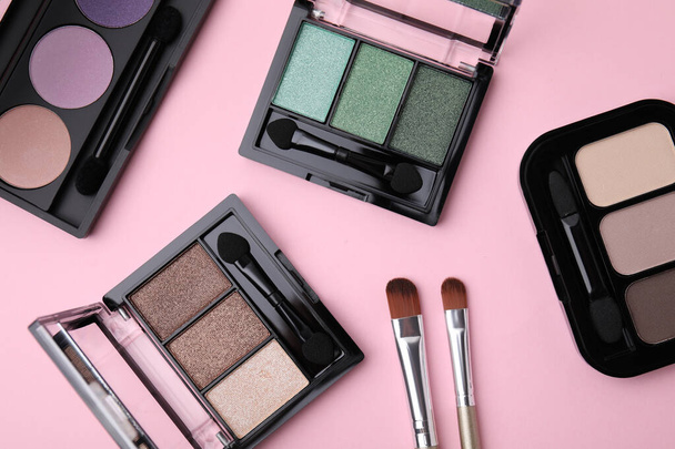 Beautiful eye shadow palettes and brushes on pink background, flat lay - Foto, immagini