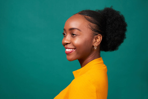 Mooie zwarte vrouw glimlachend in studio, teal achtergrond, mode lifestyle portret. Hoge kwaliteit foto - Foto, afbeelding