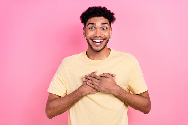 Photo of overjoyed astonished impressed guy wear yellow t-shirt hold hands on heart unbelievable luck isolated on pink color background. - Foto, imagen