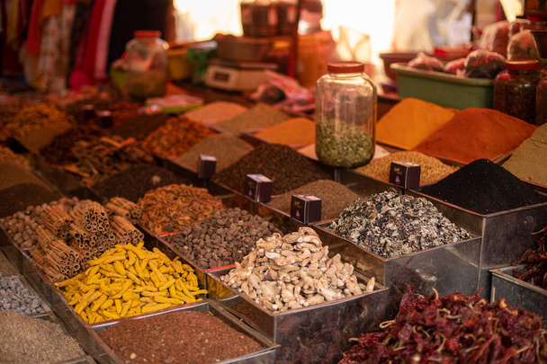 Seasonings and spices in assortment laid out in big, square containers and selling at Goa market. Powdered, whole and mixed flavorings, nuts and seeds on commerce in India.  - Photo, Image