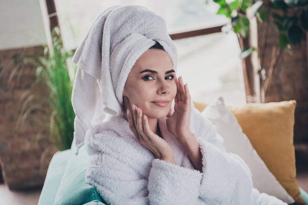Photo of young lady after bath sit sofa in modern spa studio interior touch fingers face enjoy fresh flawless skin gel. - Foto, Bild
