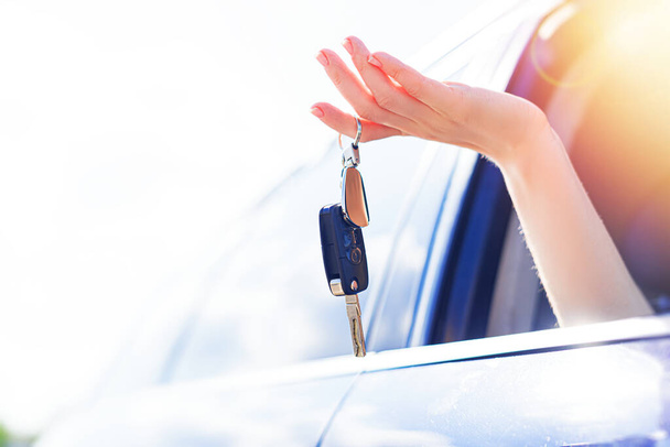 A beautiful blonde woman holds a car key in her hand. Woman car driver. - 写真・画像